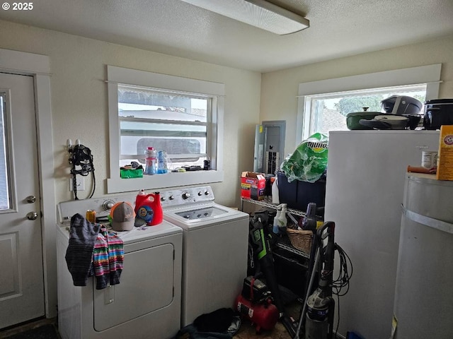 laundry room with a textured ceiling, laundry area, washing machine and clothes dryer, and electric panel