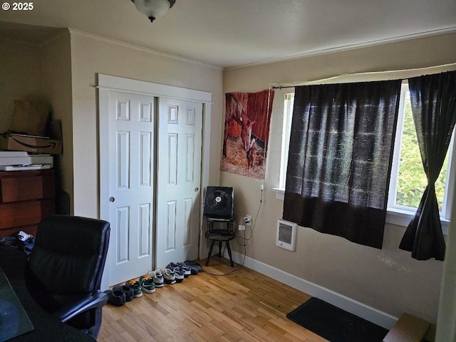 office featuring heating unit, crown molding, baseboards, and wood finished floors