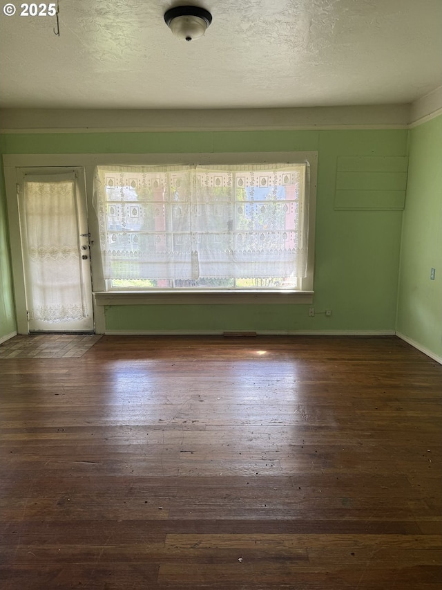 unfurnished room with a textured ceiling, visible vents, and hardwood / wood-style floors