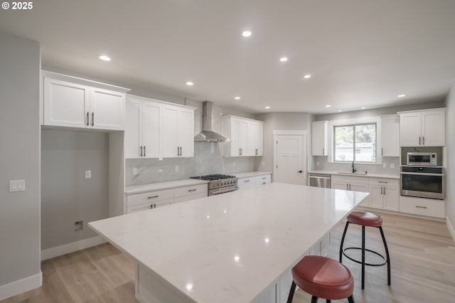 7320 Tanglewood Ave, Gleneden Beach, OR 97388 - kitchen with stainless steel appliances, wall chimney range hood, a large island, a breakfast bar, and white cabinetry