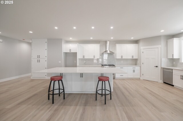 7320 Tanglewood Ave, Gleneden Beach, OR 97388 - kitchen with wall chimney exhaust hood, appliances with stainless steel finishes, light wood-style flooring, backsplash, and light countertops