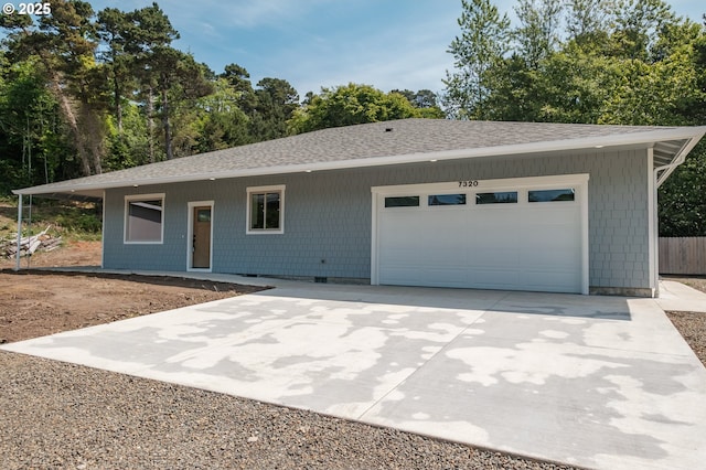 7320 Tanglewood Ave, Gleneden Beach, OR 97388 - ranch-style house with roof with shingles, an attached garage, concrete driveway, and view of wooded area