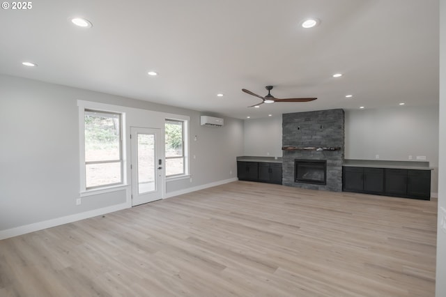 7320 Tanglewood Ave, Gleneden Beach, OR 97388 - unfurnished living room featuring a wall mounted air conditioner, recessed lighting, light wood-style flooring, ceiling fan, and a fireplace