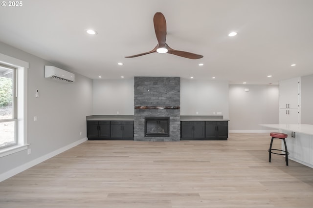 7320 Tanglewood Ave, Gleneden Beach, OR 97388 - unfurnished living room featuring a wall mounted AC, recessed lighting, light wood-type flooring, a ceiling fan, and a fireplace