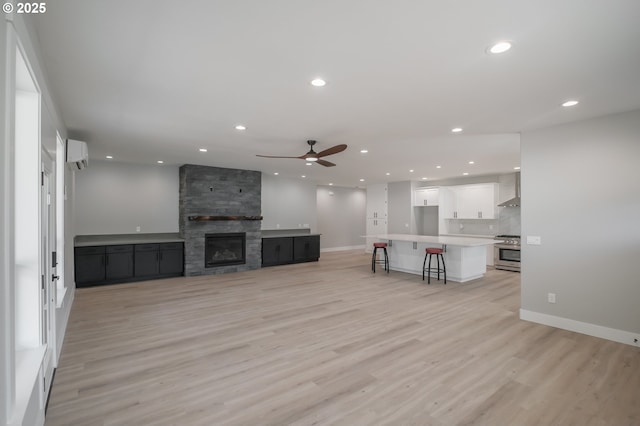 7320 Tanglewood Ave, Gleneden Beach, OR 97388 - unfurnished living room featuring an AC wall unit, a ceiling fan, recessed lighting, light wood-type flooring, and a fireplace