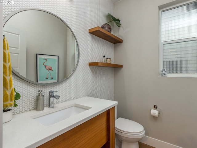 bathroom featuring backsplash, baseboards, vanity, and toilet