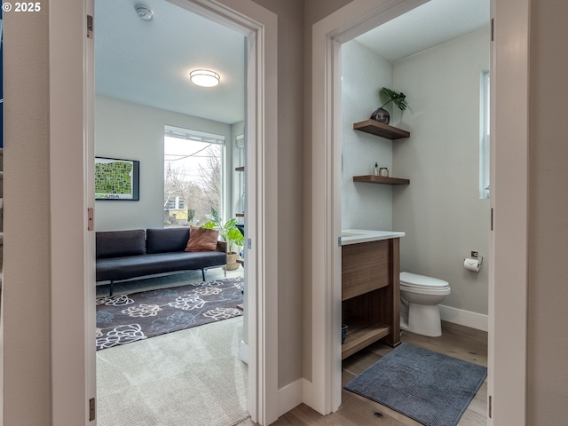 bathroom with baseboards, vanity, toilet, and wood finished floors