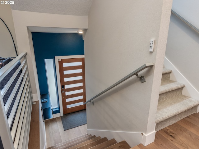 stairs with a textured ceiling and wood finished floors