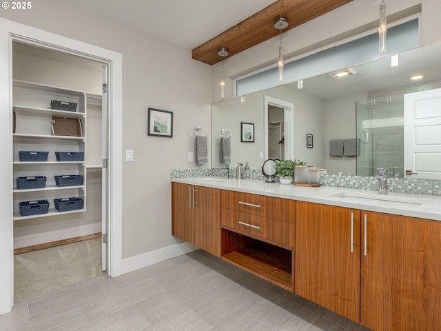 full bathroom featuring a sink, double vanity, tasteful backsplash, a stall shower, and a walk in closet