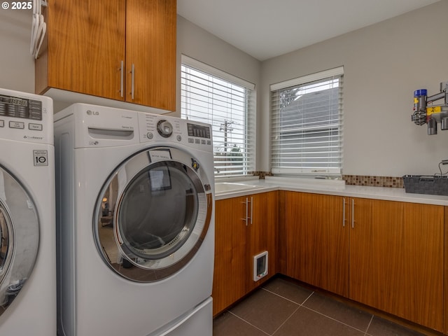 laundry room with dark tile patterned flooring, cabinet space, and washing machine and clothes dryer