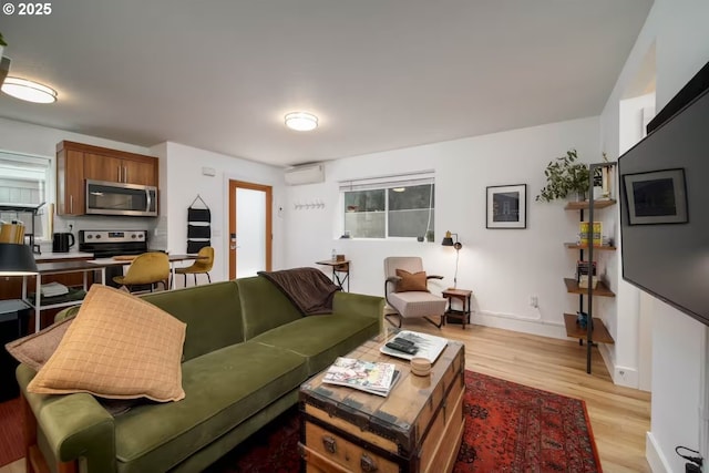 living room with light wood-style flooring, baseboards, and a wall mounted AC