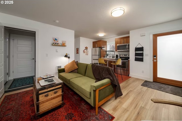 living area with light wood-style floors, baseboards, and visible vents