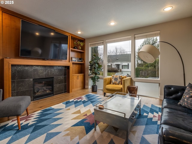 living room featuring a tile fireplace, recessed lighting, and wood finished floors