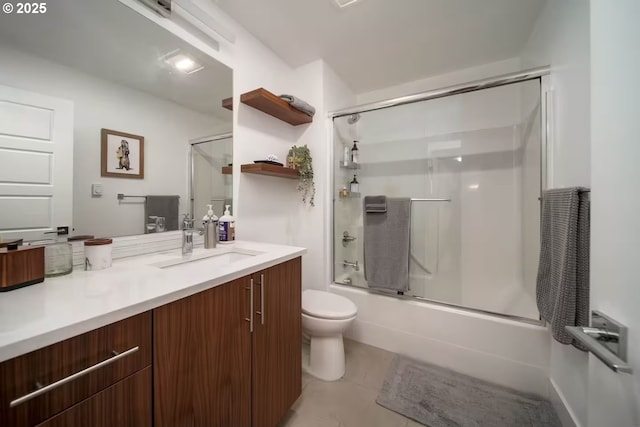 bathroom featuring toilet, tile patterned floors, combined bath / shower with glass door, and vanity