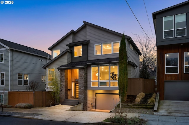 contemporary house featuring driveway, a garage, fence, and brick siding