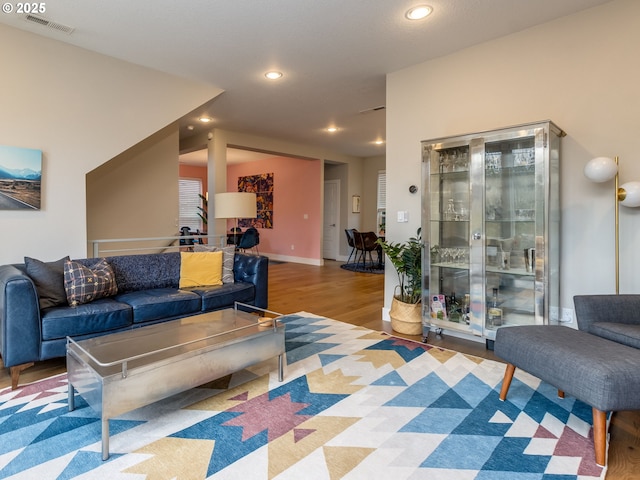 living area with recessed lighting, visible vents, baseboards, and wood finished floors