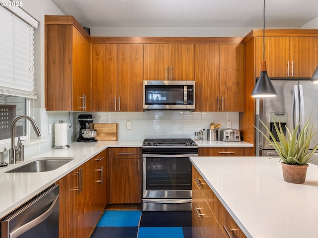 kitchen featuring stainless steel appliances, brown cabinets, light countertops, and a sink