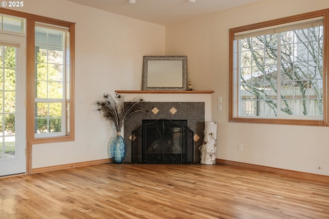 living area with wood finished floors, a tile fireplace, and baseboards