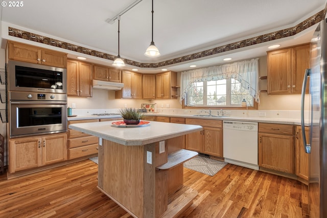 kitchen featuring light wood-style flooring, white appliances, a sink, and under cabinet range hood