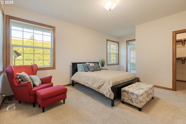 bedroom with baseboards, carpet flooring, visible vents, and a walk in closet