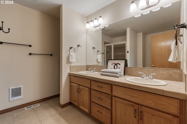 bathroom featuring a stall shower, tile patterned flooring, a sink, and visible vents