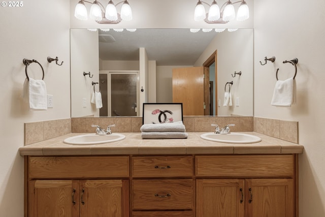 full bathroom with double vanity, a stall shower, and a sink