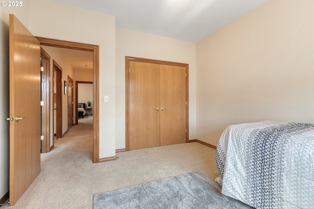 bedroom featuring a closet, light colored carpet, and baseboards