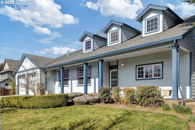 cape cod-style house with an attached garage, a shingled roof, and a front lawn