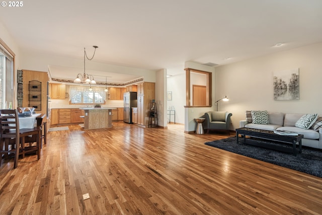 living room with light wood-style floors, visible vents, and an inviting chandelier