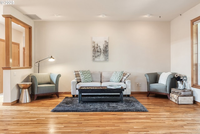 living area with wood finished floors, visible vents, and baseboards