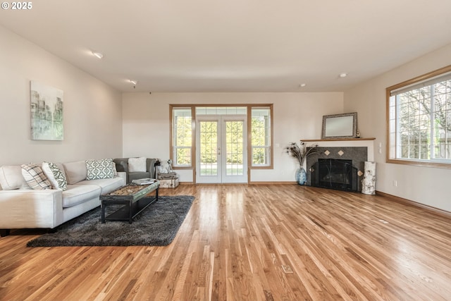 living area with french doors, wood finished floors, a tile fireplace, and baseboards