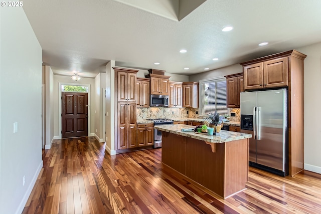 3881 SW Eleven Mile Ave, Gresham, OR 97080 - kitchen featuring stainless steel appliances, decorative backsplash, dark wood finished floors, light stone counters, and a kitchen island