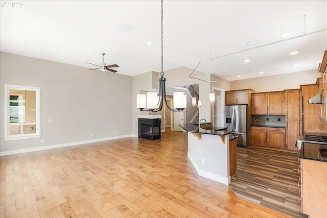 32092 SW Willamette Way E, Wilsonville, OR 97070 - kitchen with stainless steel fridge, light wood-style flooring, dark countertops, open floor plan, and recessed lighting