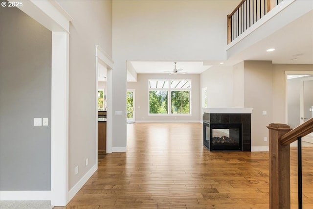 32092 SW Willamette Way E, Wilsonville, OR 97070 - unfurnished living room with wood-type flooring, a high ceiling, baseboards, a tiled fireplace, and a ceiling fan