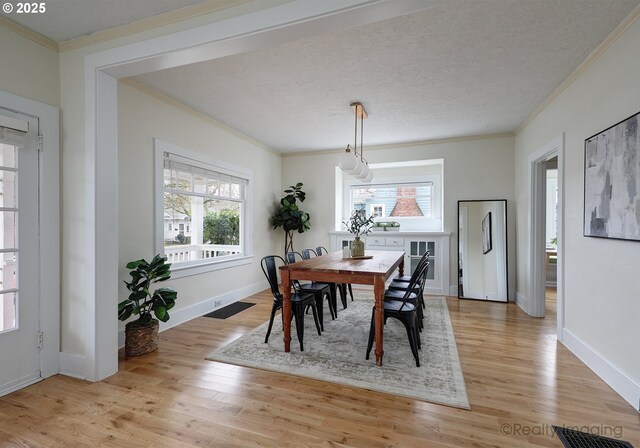 dining area featuring a notable chandelier, ornamental molding, light hardwood / wood-style flooring, and a healthy amount of sunlight