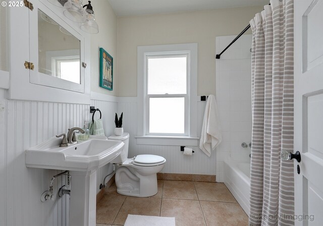 full bathroom featuring toilet, tile patterned floors, shower / bath combo, and a healthy amount of sunlight