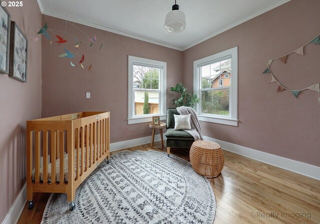 bedroom with a crib, hardwood / wood-style flooring, and crown molding