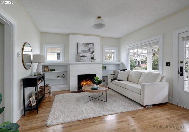 living room with a brick fireplace, a textured ceiling, light hardwood / wood-style flooring, and a healthy amount of sunlight