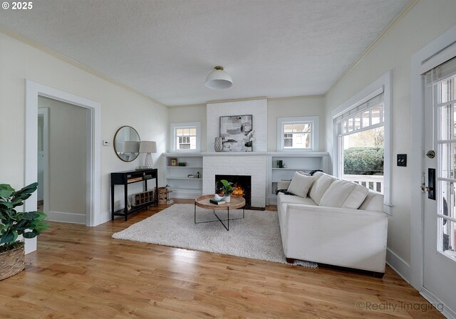 living room featuring a brick fireplace, a textured ceiling, a healthy amount of sunlight, and hardwood / wood-style flooring