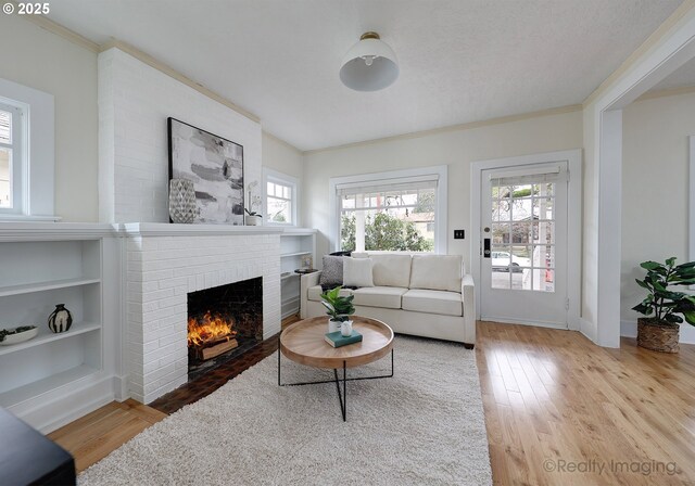 living room with a textured ceiling, light wood-type flooring, and a fireplace