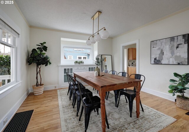 dining area featuring crown molding, light hardwood / wood-style flooring, and a healthy amount of sunlight