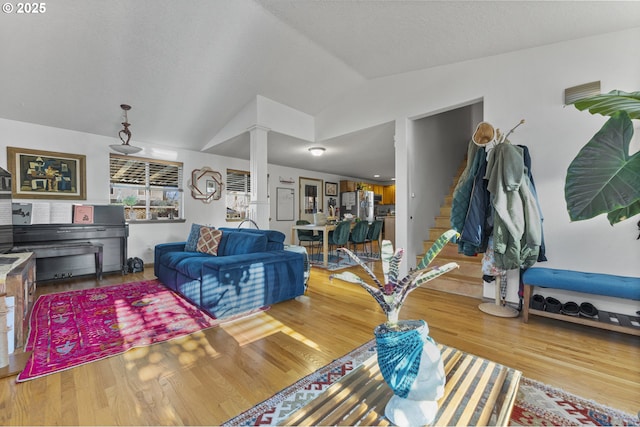 living room with ornate columns, lofted ceiling, and wood finished floors