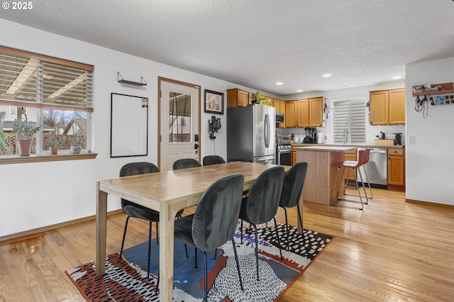 dining space with recessed lighting, baseboards, a textured ceiling, and light wood finished floors