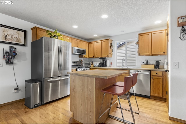 kitchen featuring light countertops, a center island, light wood-type flooring, and stainless steel appliances