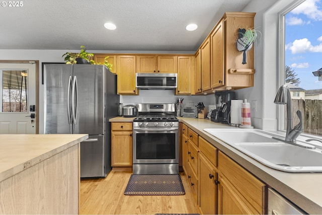 kitchen featuring recessed lighting, a sink, light countertops, appliances with stainless steel finishes, and light wood-type flooring