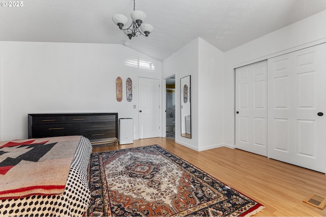 bedroom featuring visible vents, baseboards, a chandelier, vaulted ceiling, and light wood-style floors