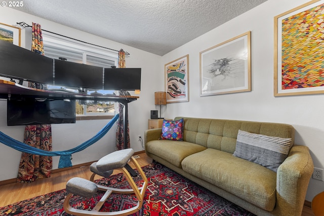 living area with wood finished floors, baseboards, and a textured ceiling