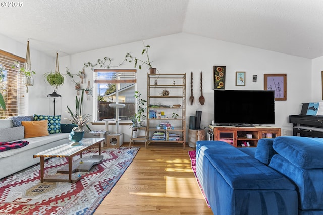 living area with lofted ceiling, wood finished floors, and a textured ceiling