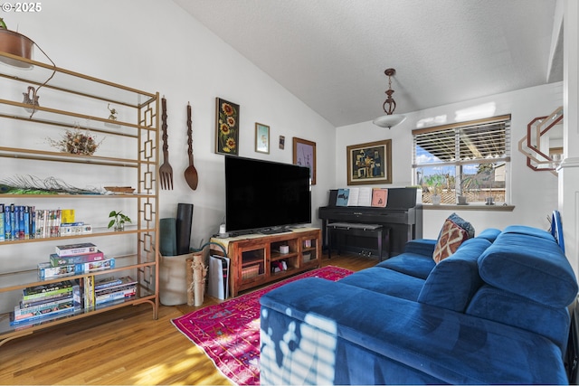 living room with a textured ceiling, lofted ceiling, and wood finished floors