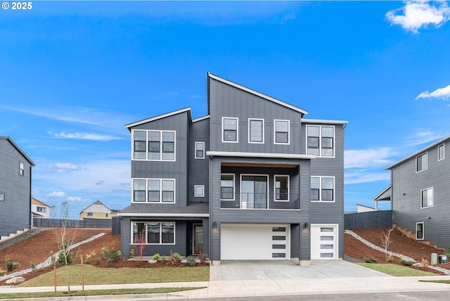 contemporary house featuring a balcony, a garage, fence, driveway, and board and batten siding